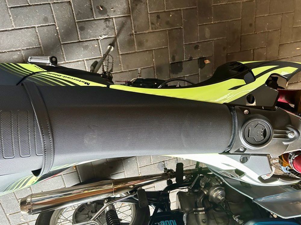 Nahaufnahme eines schwarz-neongrünen Motorradsitzes und des Heckteils in einer Garage.