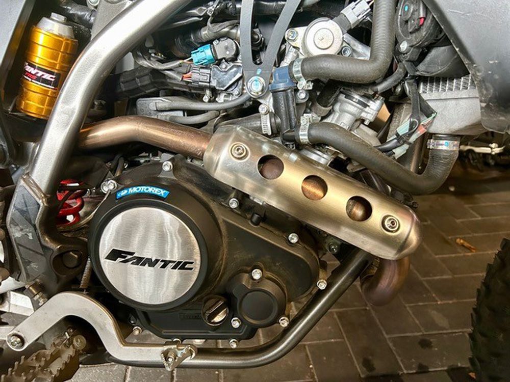 Nahaufnahme eines Oldtimer-Motorradmotors der Marke PANTIC mit verchromtem Auspuff und goldenen Fahrwerkskomponenten.