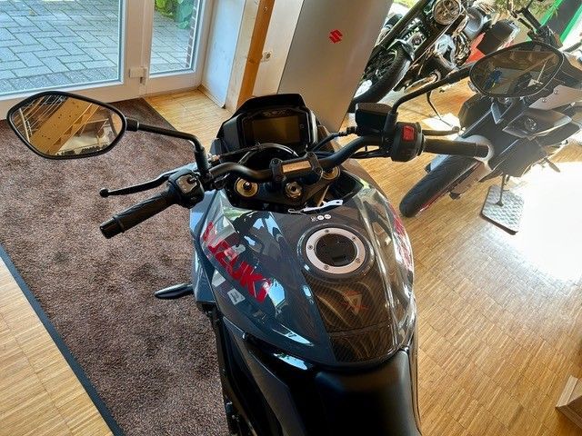 Schwarzes Sportmotorrad, das drinnen auf einem Teppich neben Fenstern und einer verspiegelten Wand geparkt ist.