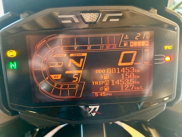 Das digitale Armaturenbrett des Motorrads leuchtet orange und zeigt Leerlauf, Geschwindigkeit 0 sowie Tages- und Kilometerzählerstand an.