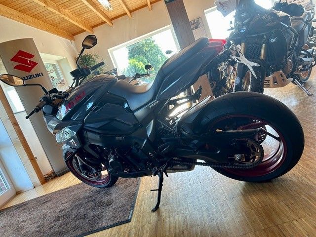 Schwarzes Motorrad parkt drinnen in der Nähe einer Tür, durch die Sonnenlicht hereinströmt.