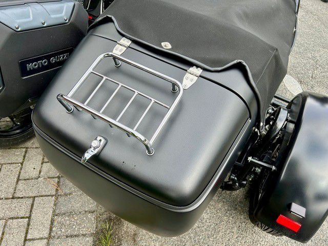 Schwarzes Motorradgespann mit Gepäckträger, das auf dem Bürgersteig parkt.