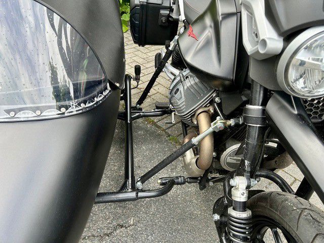 Nahaufnahme von zwei geparkten Motorrädern mit silbernen und schwarzen Beiwagenrahmen und sichtbaren Motorteilen