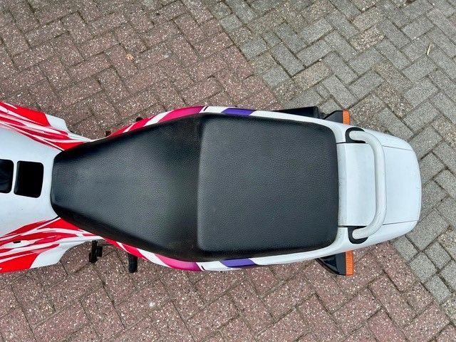 Draufsicht auf ein rot-weißes Motorrad mit schwarzem Sitz auf einer gepflasterten Auffahrt