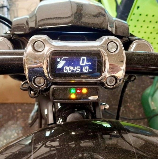 Motorrad-Armaturenbrett mit digitalem Tachometer, Kontrollleuchten und schwarzem Lenker.