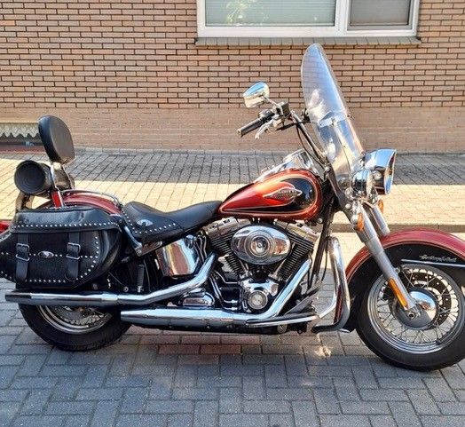 Schwarzes Cruiser-Motorrad mit Windschutzscheibe, Satteltaschen und Soziuslehne parkt auf einem Ziegelpflaster.