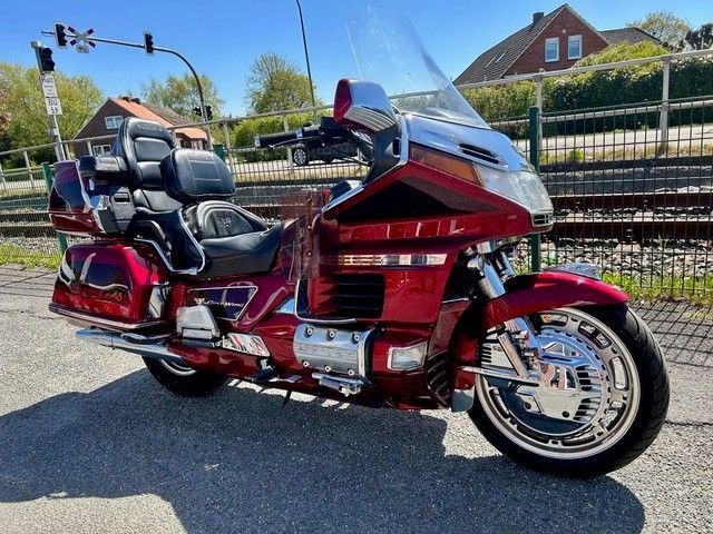 Rotes Tourenmotorrad mit Windschutzscheibe, das im Sonnenlicht auf einer Straße geparkt ist