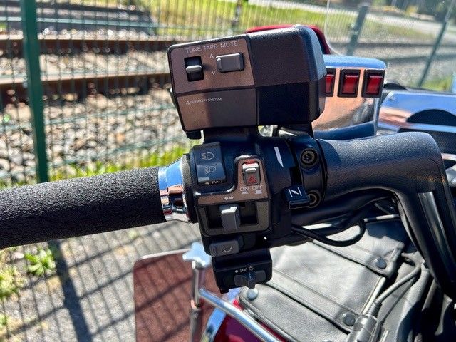 Nahaufnahme einer am Lenker montierten Action-Kamera und deren Bedienelemente an einem Roller oder Motorrad im Freien.