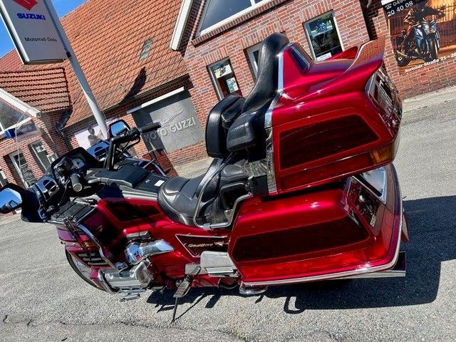 Ein rotes dreirädriges Motorrad parkte auf einer Straße neben Backsteingebäuden.