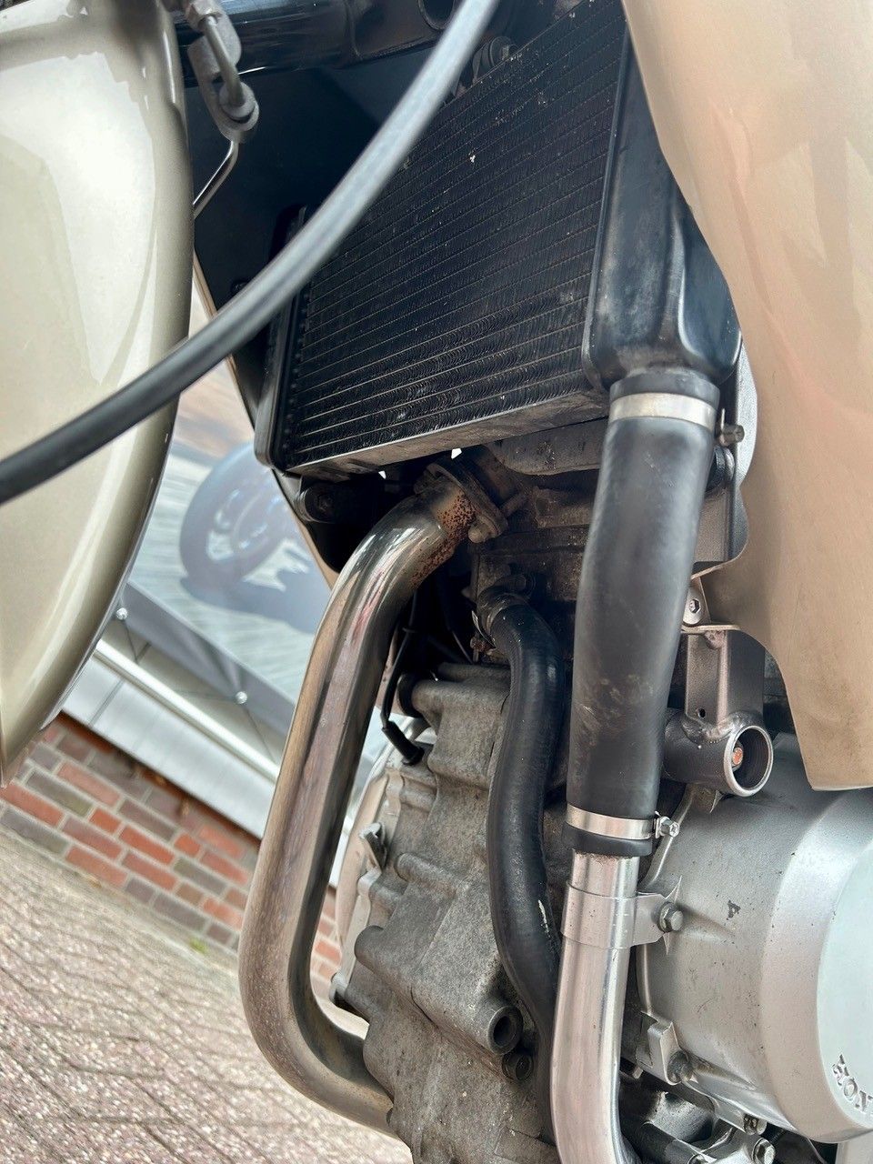 Nahaufnahme eines Motorradmotors und Auspuffrohrs mit einer Kohlefaserverkleidung.