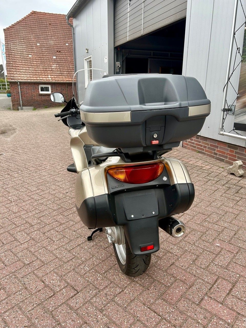 Geparkter Roller an einer Laderampe eines Lagerhauses, von hinten gesehen, mit Topcase und rotem Rücklicht.