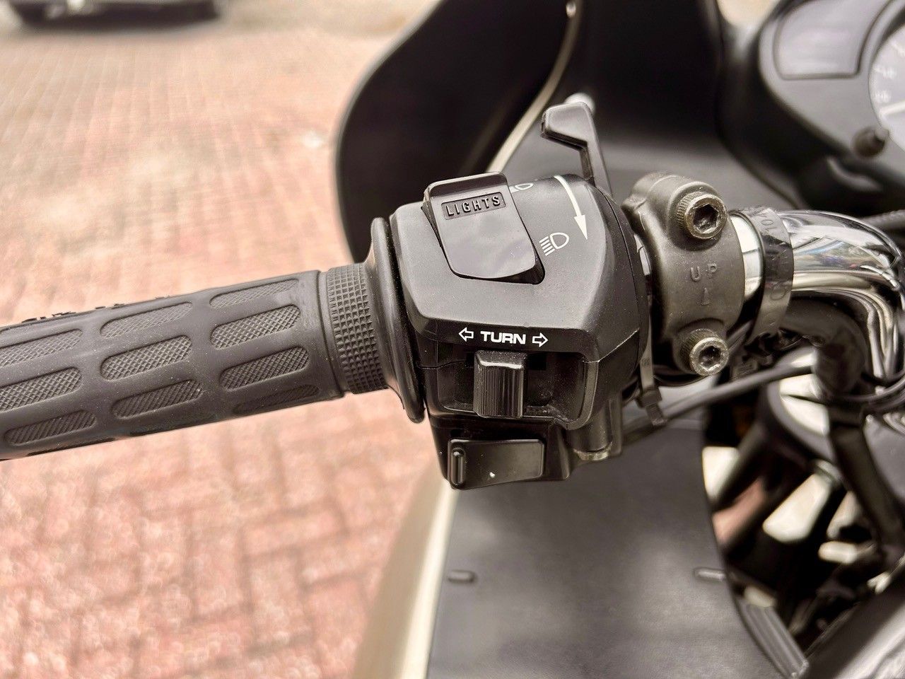 Nahaufnahme eines schwarzen Motorradlenkers mit Gasgriff und Bedienschalter neben dem Sitz