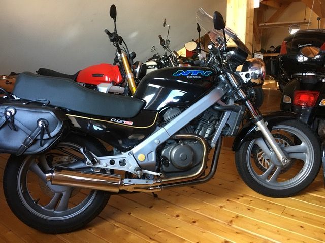 Ein schwarzes Motorrad ist auf einem Holzboden geparkt