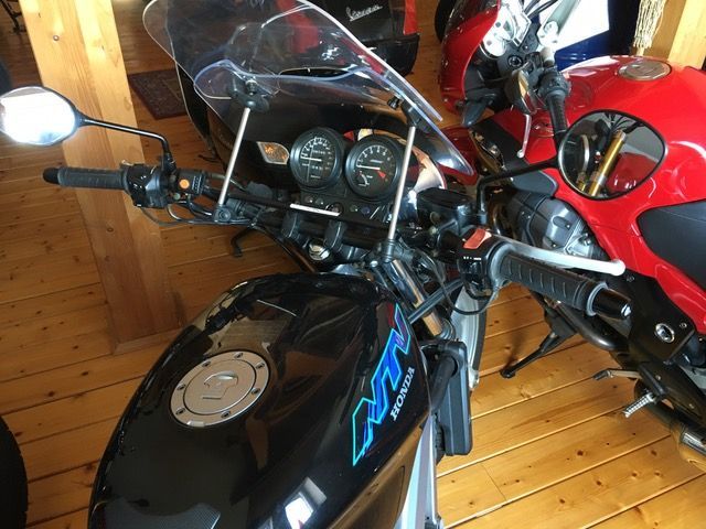Ein schwarzes Honda-Motorrad ist auf einem Holzboden geparkt