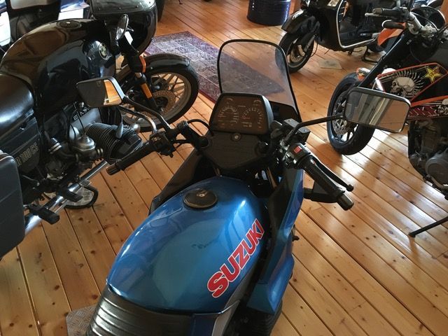 Ein blaues Suzuki-Motorrad ist auf einem Holzboden geparkt