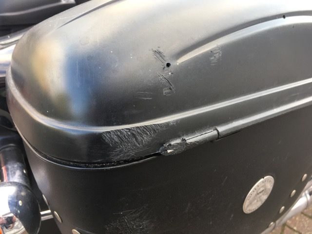 Eine Nahaufnahme einer schwarzen Motorradgepäckbox mit einem Loch darin.