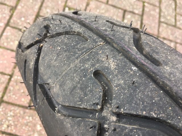 Eine Nahaufnahme eines Motorradreifens auf einem gepflasterten Gehweg.