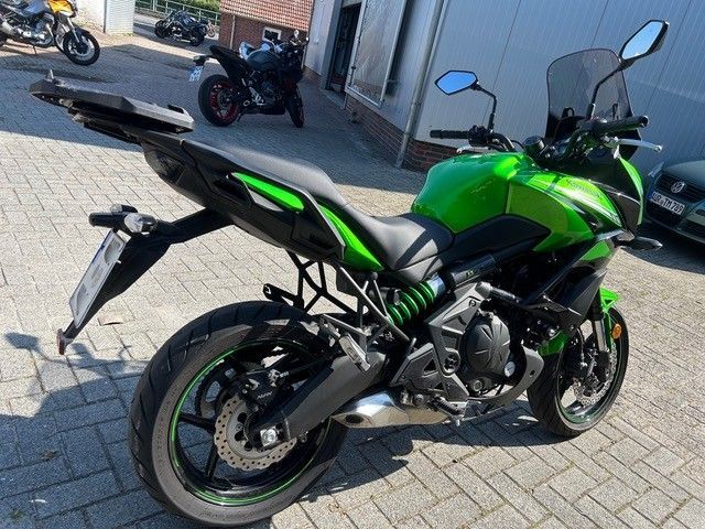 Grünes Sportmotorrad, geparkt auf einer gepflasterten Straße, Ansicht von hinten links.