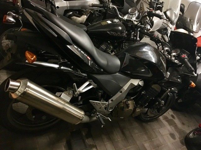 Ein schwarzes Motorrad ist in einer Garage mit anderen Motorrädern geparkt