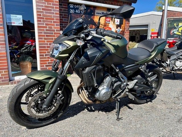 Ein grünes Sportmotorrad parkt an einem sonnigen Tag vor einem Backsteingebäude.