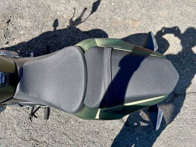 Draufsicht auf einen grün-grauen Fahrradsattel auf dem Bürgersteig, der einen Schatten wirft.