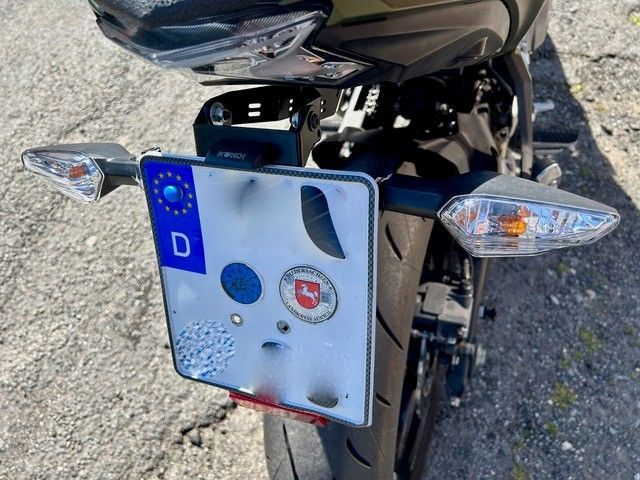 Motorradheck mit europäischem Kennzeichen und Rücklichtern, geparkt auf Schotter