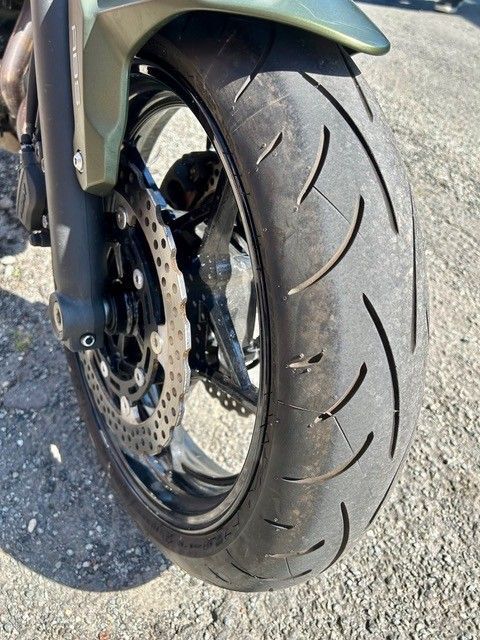 Nahaufnahme eines Motorradvorderrads und einer Bremsscheibe auf Asphalt