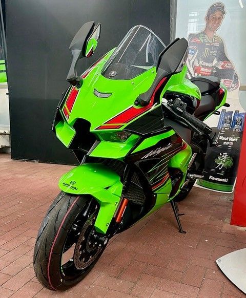 Auf einem Ziegelboden ist ein grün-rotes Motorrad geparkt.