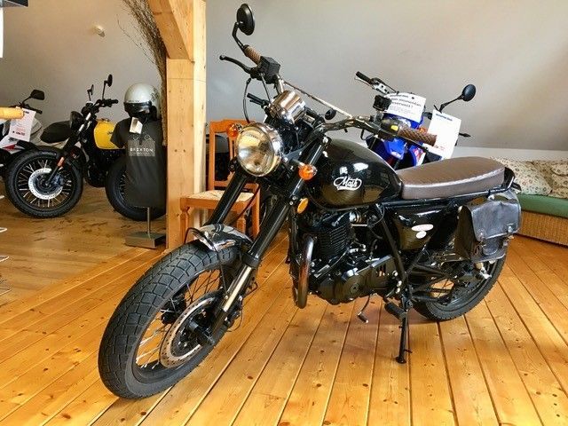 Ein Motorrad ist auf einem Holzboden in einem Raum geparkt.