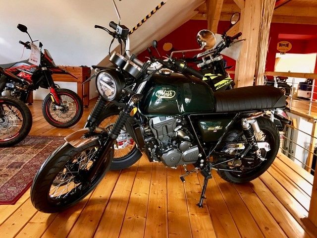 Ein grünes Motorrad ist auf einem Holzboden geparkt