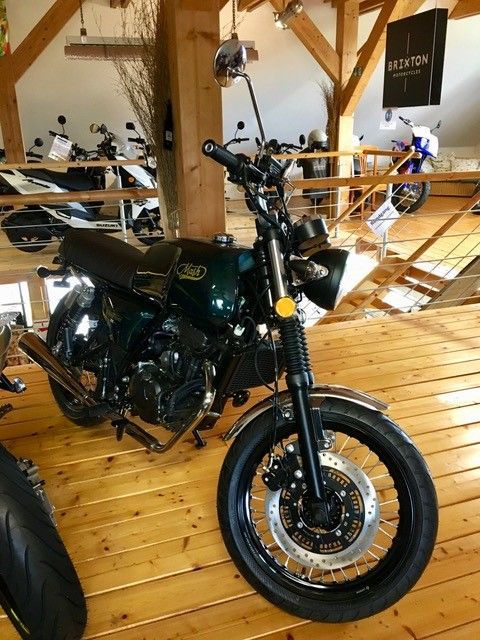 Ein grünes Motorrad ist auf einem Holzboden geparkt