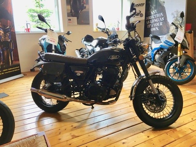 In einem Ausstellungsraum steht ein Motorrad auf einem Holzboden.