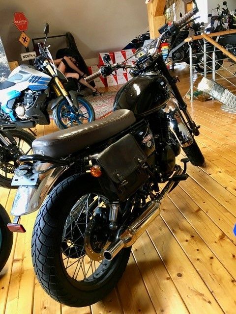 Ein schwarzes Motorrad ist auf einem Holzboden in einem Raum geparkt.