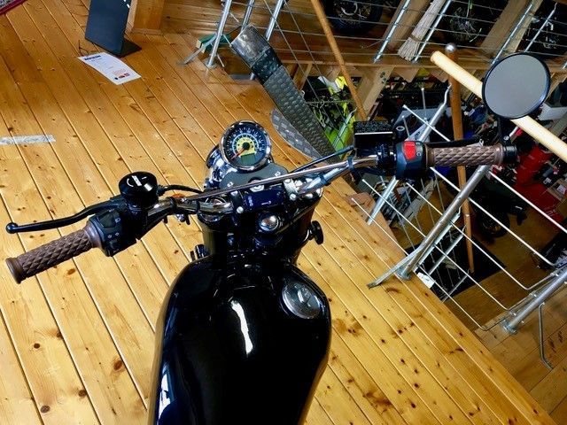 Ein schwarzes Motorrad ist auf einem Holzboden geparkt