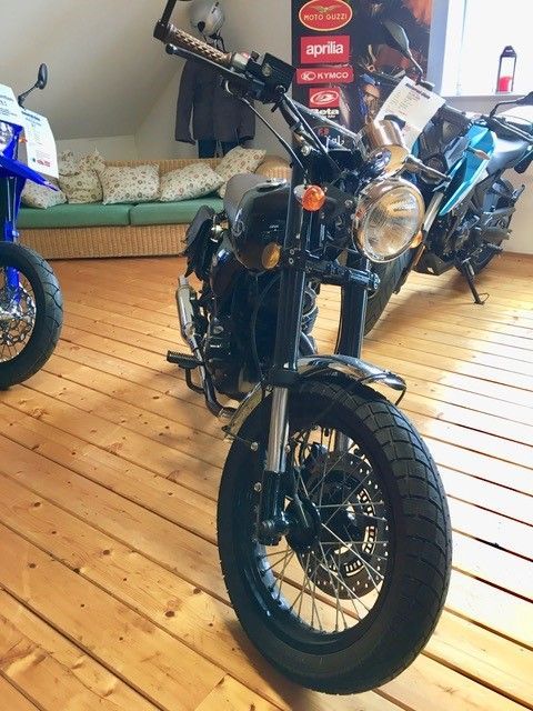 Ein Motorrad ist auf einem Holzboden in einem Raum geparkt