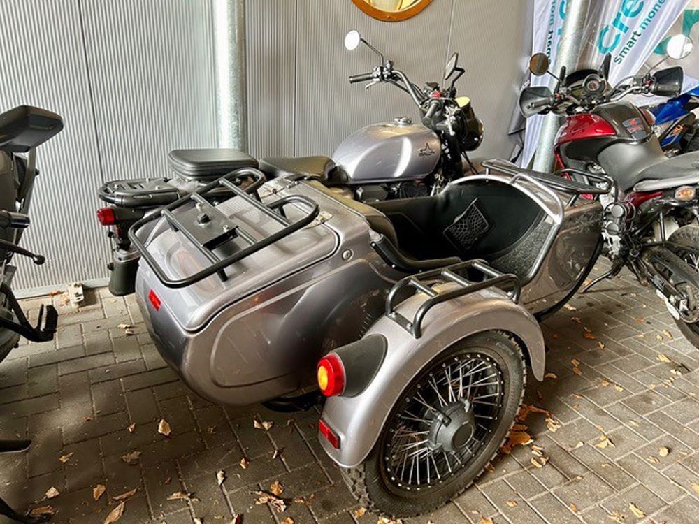 Graues dreirädriges Motorrad, geparkt unter einem Sonnensegel, mit Topcase und schwarzen Rädern