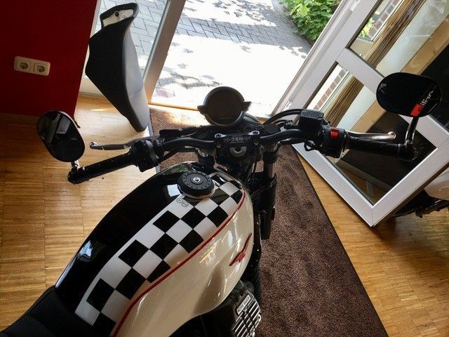 Ein schwarz-weiß kariertes Motorrad ist in einem Raum geparkt