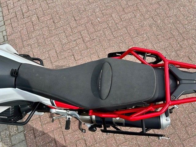 Draufsicht auf einen Motorradsitz mit rotem Gepäckträger auf einem Ziegelpflaster.