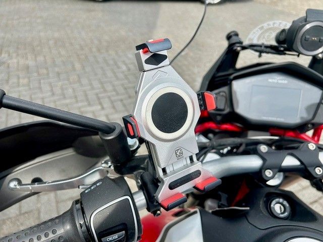 Motorradlenker mit montierter Handyhalterung und einem rot-schwarzen Fahrrad im Hintergrund