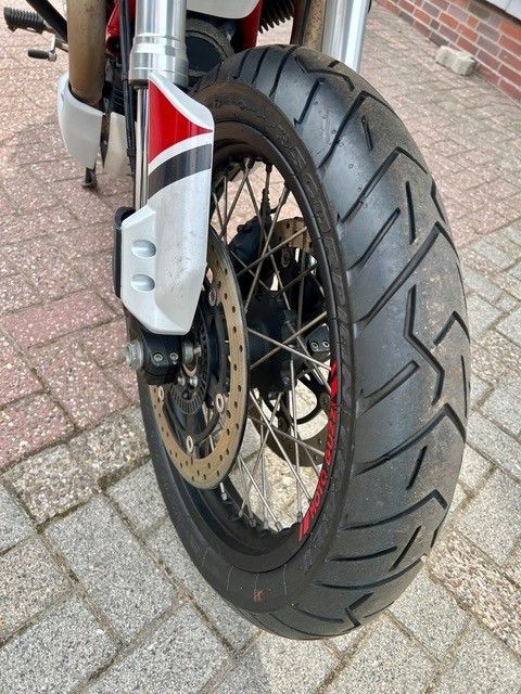 Motorradvorderrad mit Scheibenbremse und silberner Gabel auf einem Ziegelpflaster