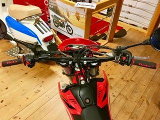 Ein rot-schwarzes Dirtbike steht auf einem Holzboden.