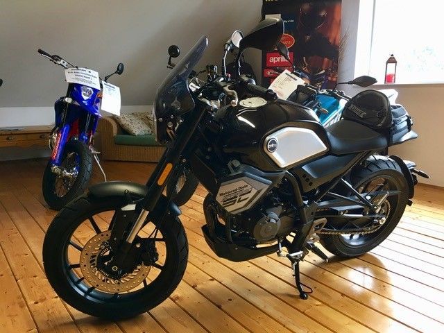 Zwei Motorräder sind auf einem Holzboden in einem Raum geparkt.