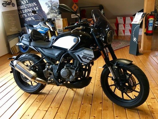 Ein schwarz-weißes Motorrad ist auf einem Holzboden geparkt