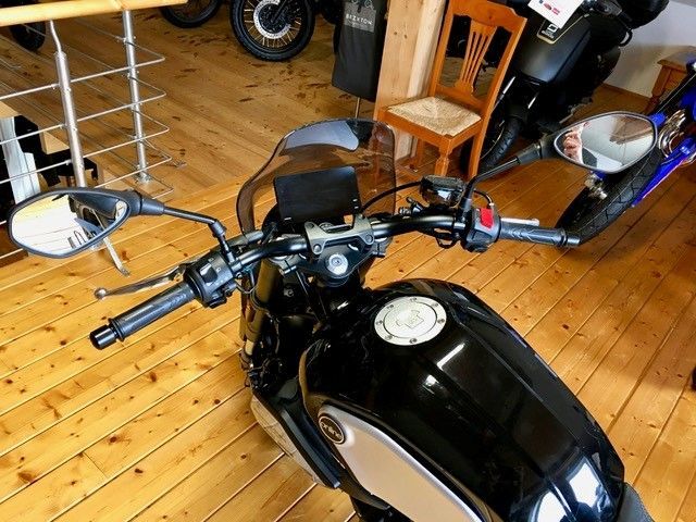 Ein schwarzes Motorrad ist auf einem Holzboden geparkt