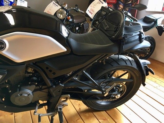 Ein schwarz-silbernes Motorrad ist auf einem Holzboden geparkt