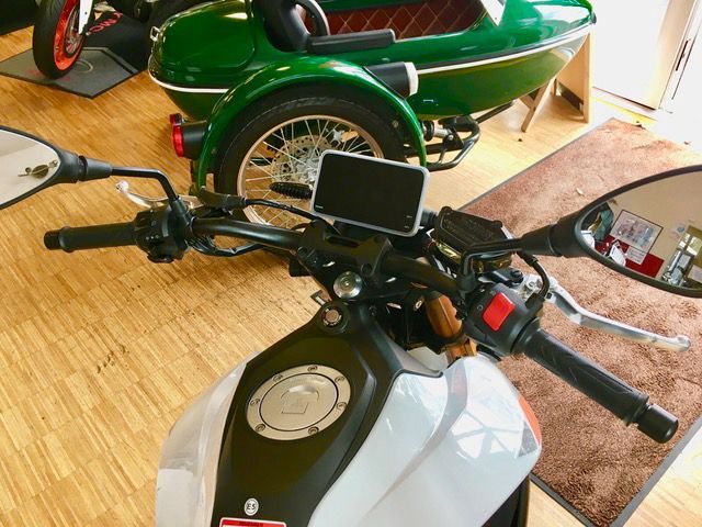 Ein Motorrad ist in einem Raum neben einem grünen Beiwagen geparkt