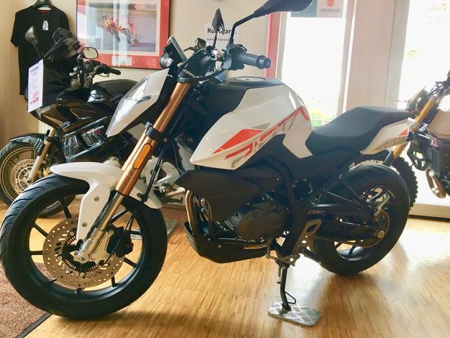 Ein weißes Motorrad ist in einem Raum mit anderen Motorrädern geparkt