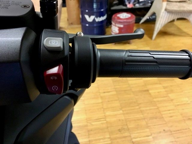 Eine Nahaufnahme eines Motorradlenkers mit einem roten Knopf darauf