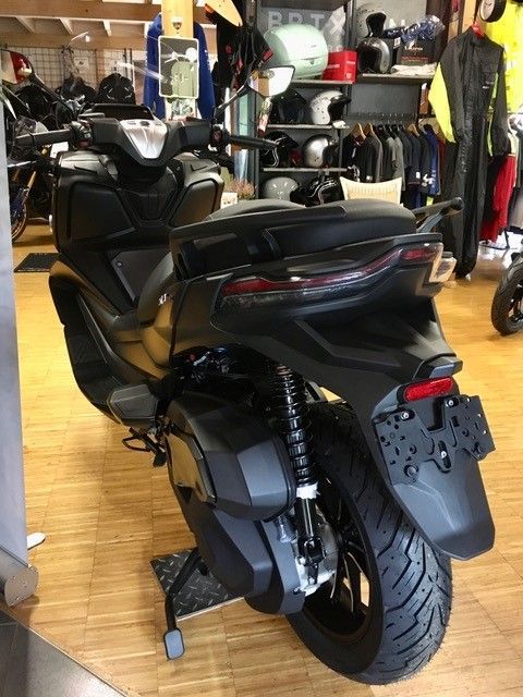 Ein schwarzer Roller steht auf einem Holzboden in einem Geschäft