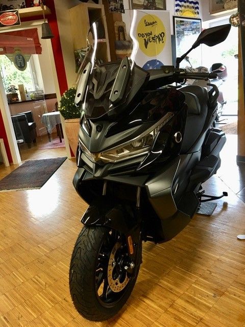 Ein Roller steht auf einem Holzboden in einem Raum